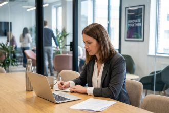 Femme en réunion au bureau avec ordinateur et notes